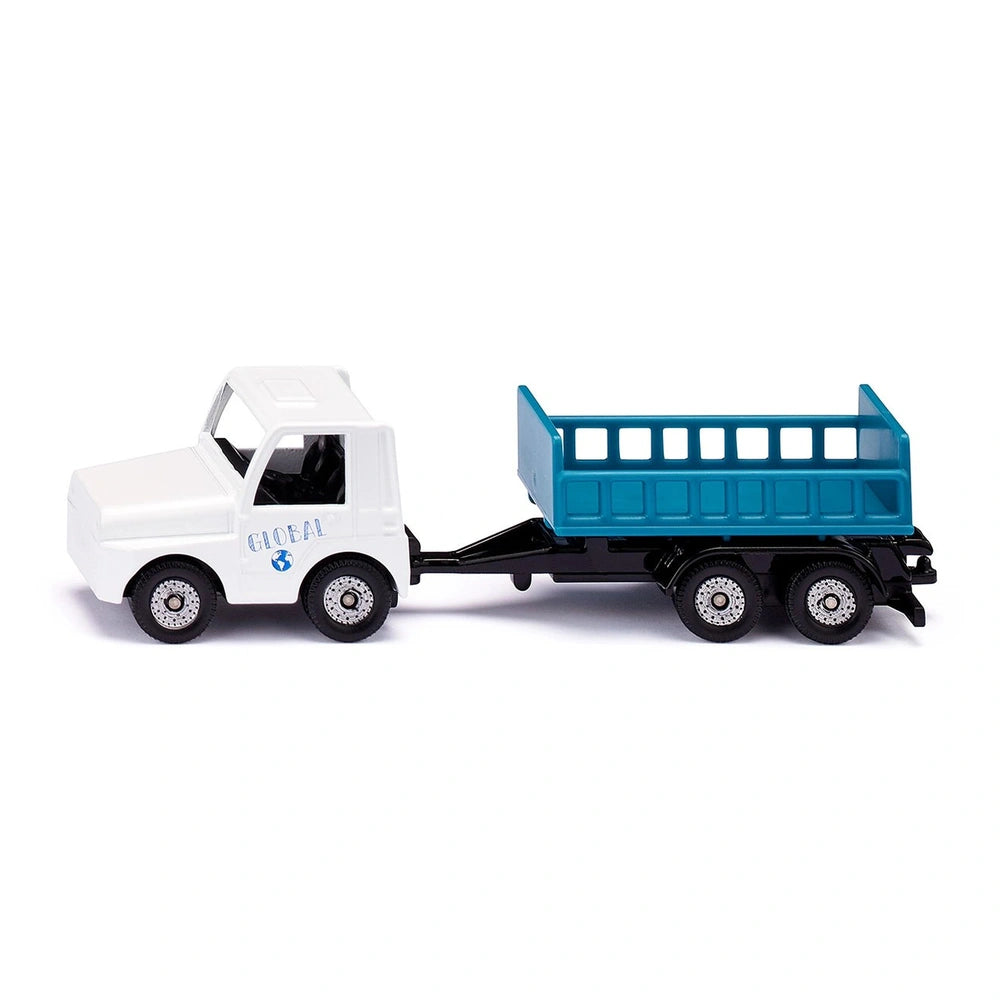 White toy truck with a blue flatbed trailer on a smooth surface, showcasing its cab and hitch connection.