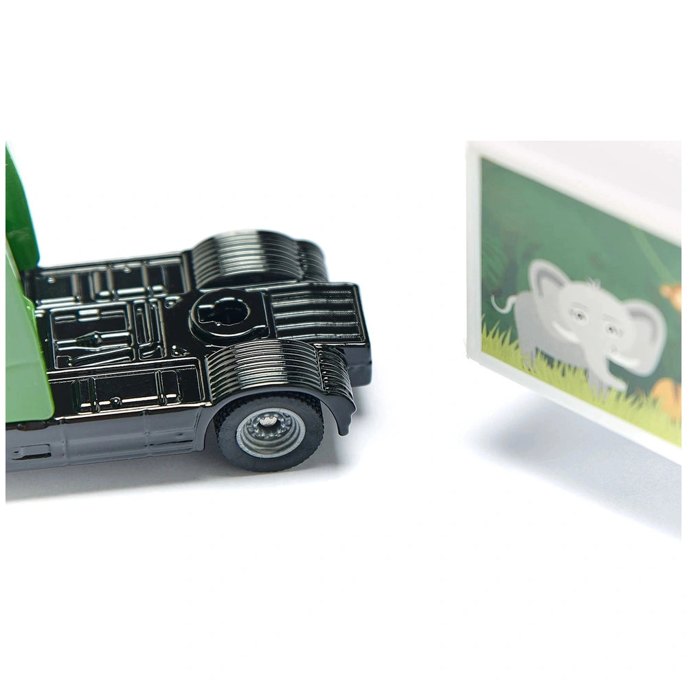 Articulated truck toy in black plastic with metallic sheen alongside a green elephant-printed trailer on a white background.