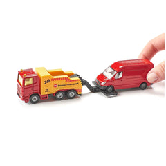 Red toy breakdown truck with yellow trailer marked "SERVICE TRANSPORT," held by a hand against a plain white background.