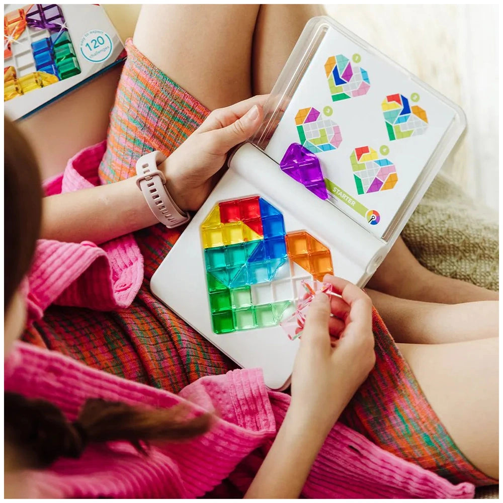 Smart Games - IQ Love logic puzzle displayed on a white laptop held by a person in a pink garment with crossed legs.