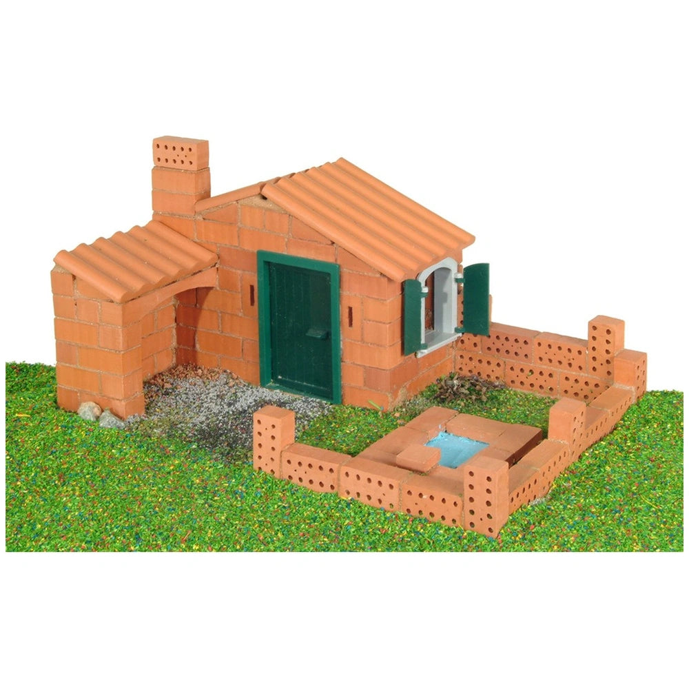 Teifoc Castle-House model features red brick walls, a green door and window frames, with a corrugated brown roof on green gra