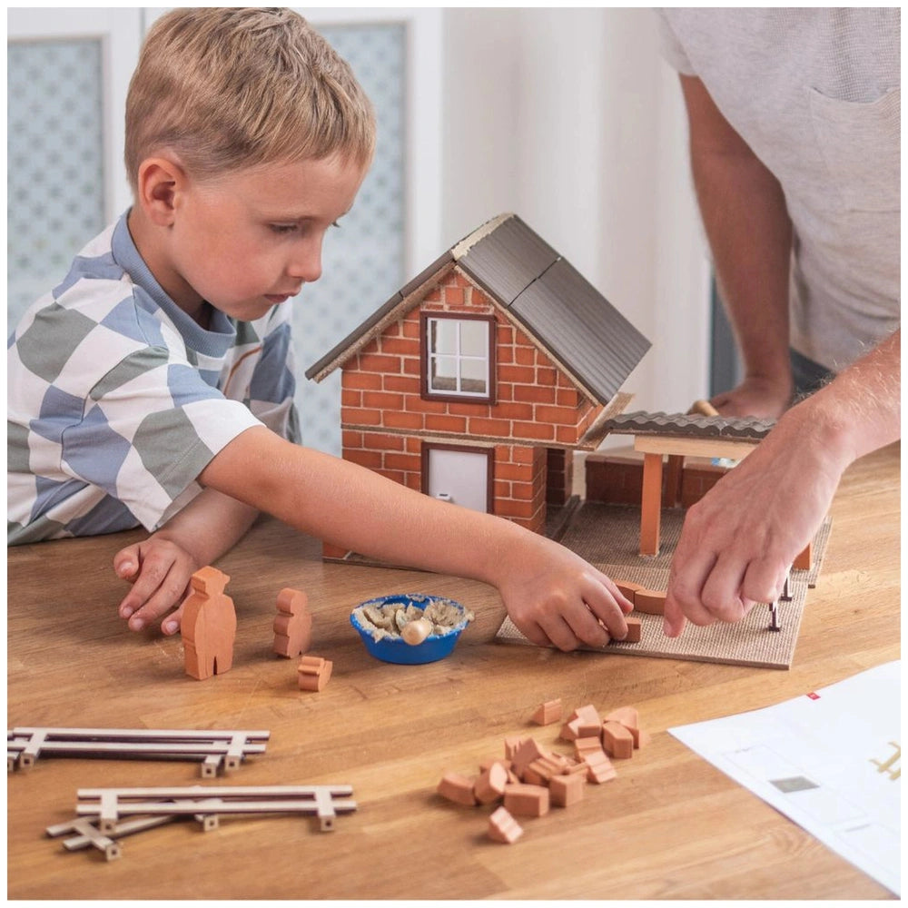Teifoc wooden farm model set is being assembled by a child at a wooden table with scattered pieces and an adult nearby.
