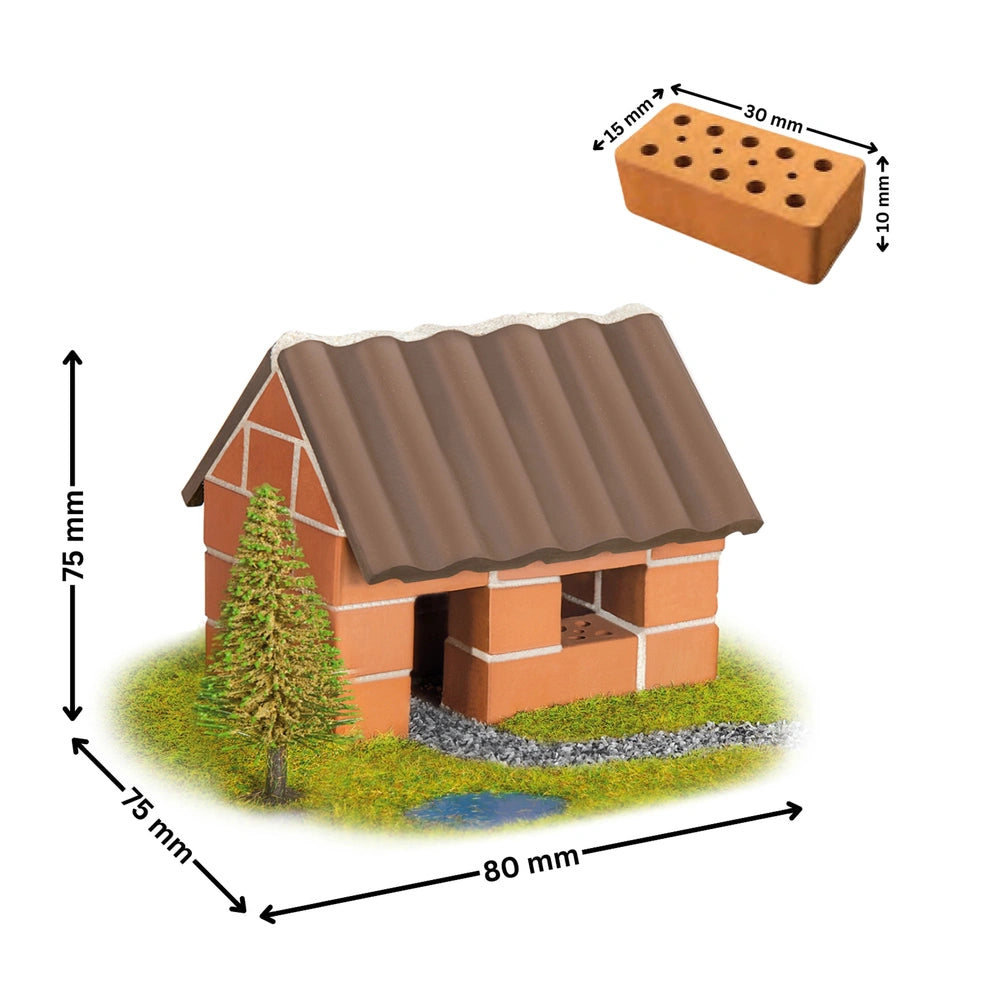 Teifoc small brick house model with a brown shingled roof on vibrant green grass beside a clear puddle of water.