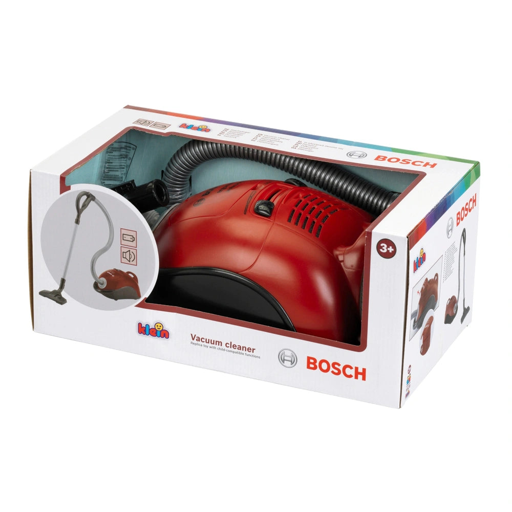 Red and black Bosch vacuum cleaner with hose, nozzle, dust bag, and wheels in cardboard retail packaging.