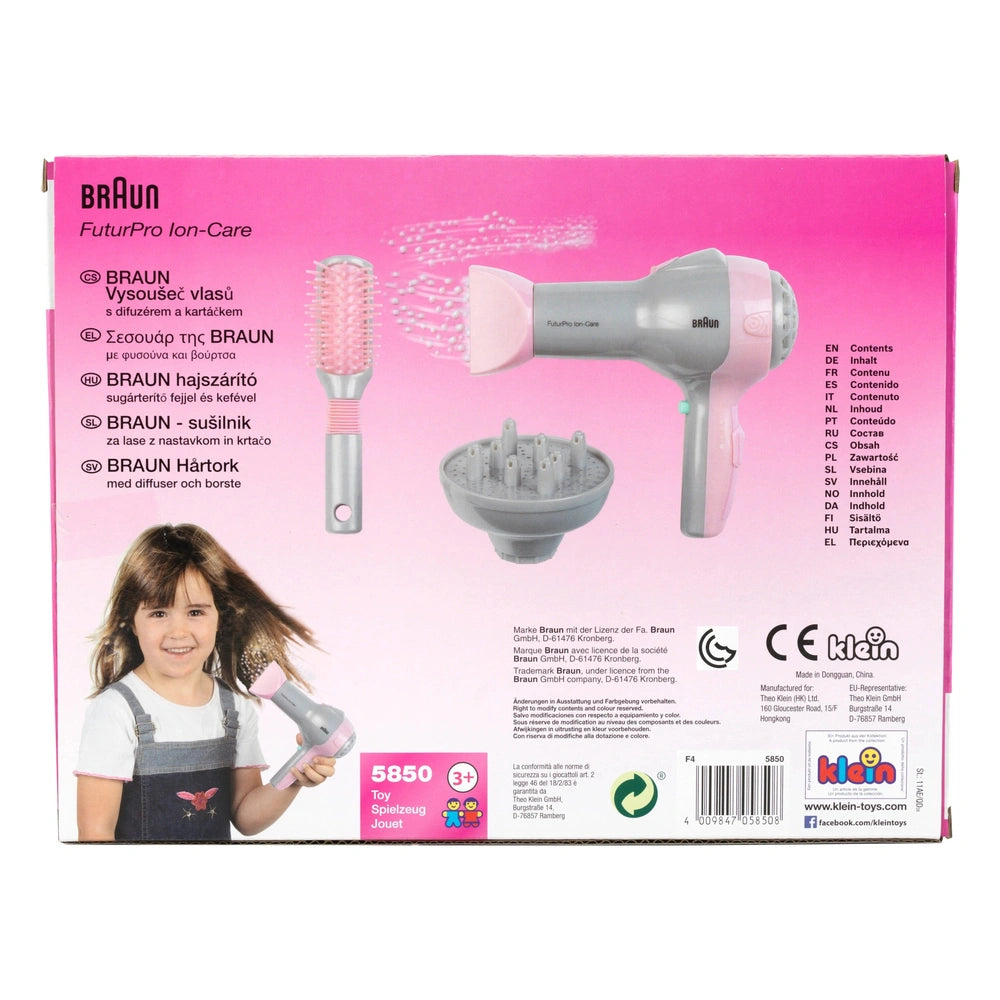 Theo Klein Braun hairdryer with pink and white design, includes diffuser, brush, and comb attachments in glossy retail packag