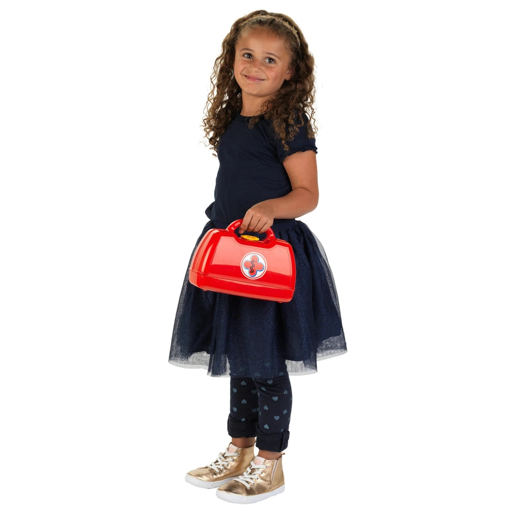 a red lunch box with a white cross, held by a young girl in a dark blue outfit and light gold shoes.