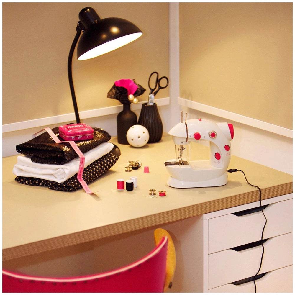 Theo Klein kids sewing machine in a lifestyle scene on a wooden desk, featuring pink and black polka dot fabrics and scissors