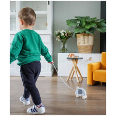 TRYCO Wooden Elephant Pull Along Toy being held by a child in a green shirt, next to a white vase with flowers.