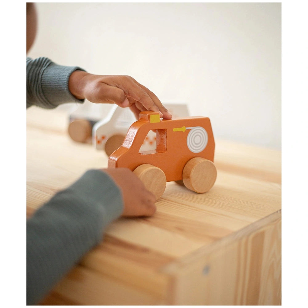 TRYCO Wooden Game Fire Brigade features an orange toy truck with plastic wheels and windows on a brown wooden table.